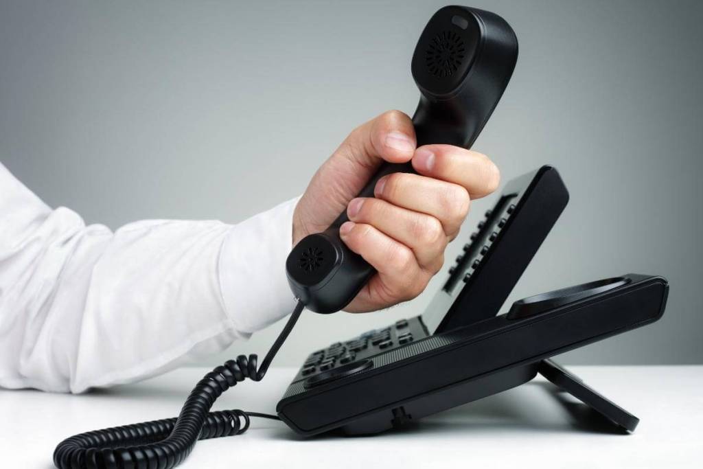 Multi-phone Systems Cost_Black business telephone, employee picking up a customer call on a VoIP phone