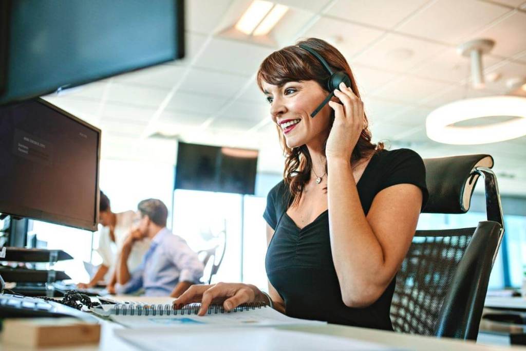 Call Center for Ecommerce Featured Image- Woman working in a call center for e-commrece, call center business; woman talking with a headset on. Customer Service role in a call center