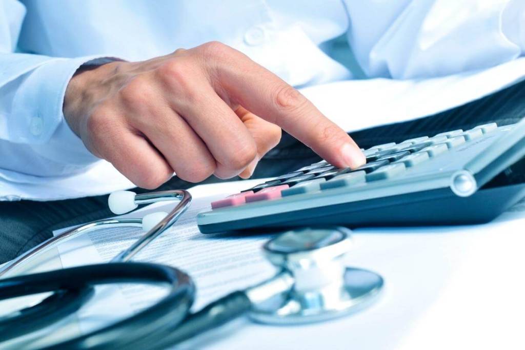 Invoice Outsourcing - Featured Image - Healthcare professiona calculating invoice and billing statement using an electronic calculator. Healthcare, medical billing, invoice process