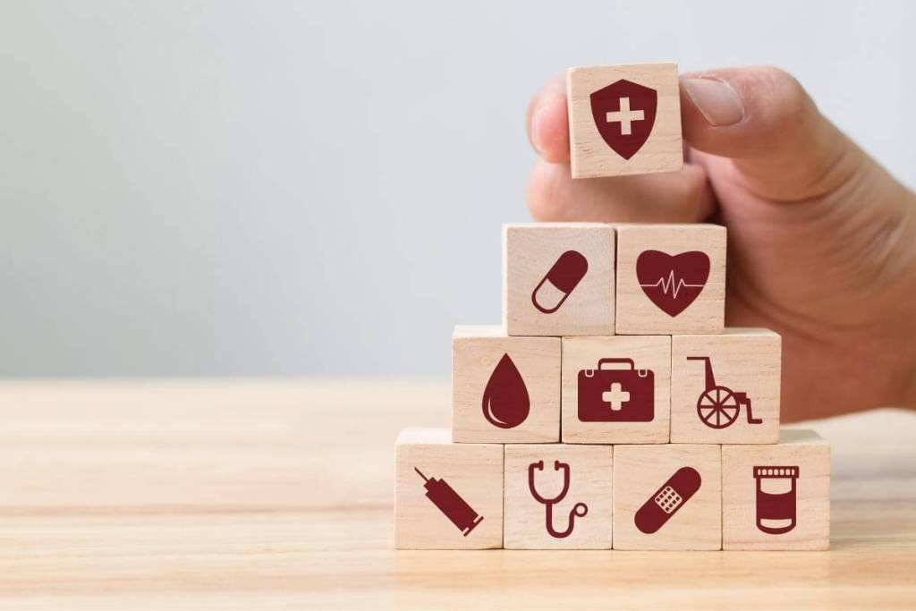 Ten Reasons to Outsource Medical Billing_Hand arranging wood block stacking with icons for healthcare,medical billing, insurance, claims processing. 