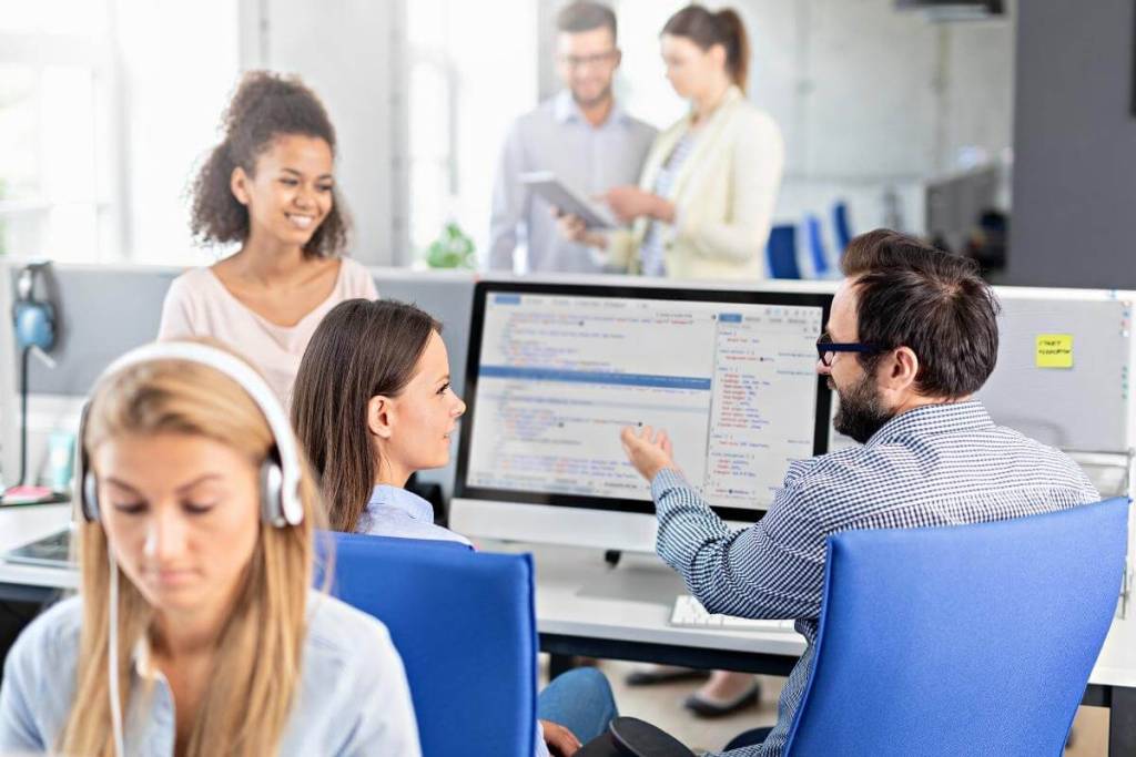 Call center support agents with supervisor discussing after call details. 