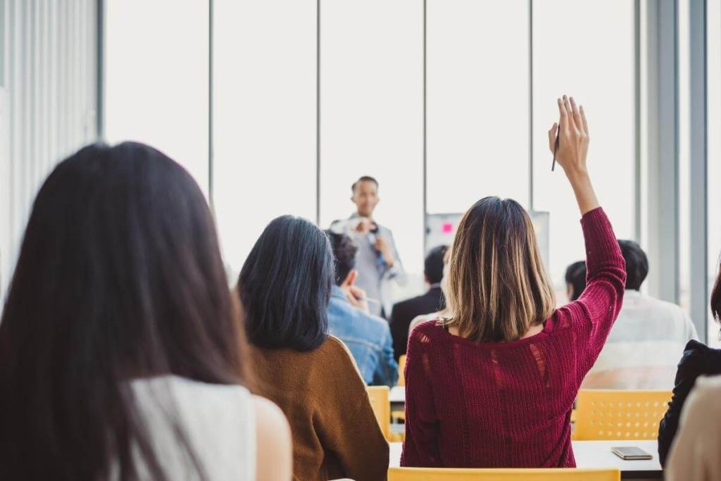 How Can Outsourcing Dermatology Medical Billing Services Be Done Successfully_back view of business woman raising hand for asking speaker for questions and answer, outsourcing meeting