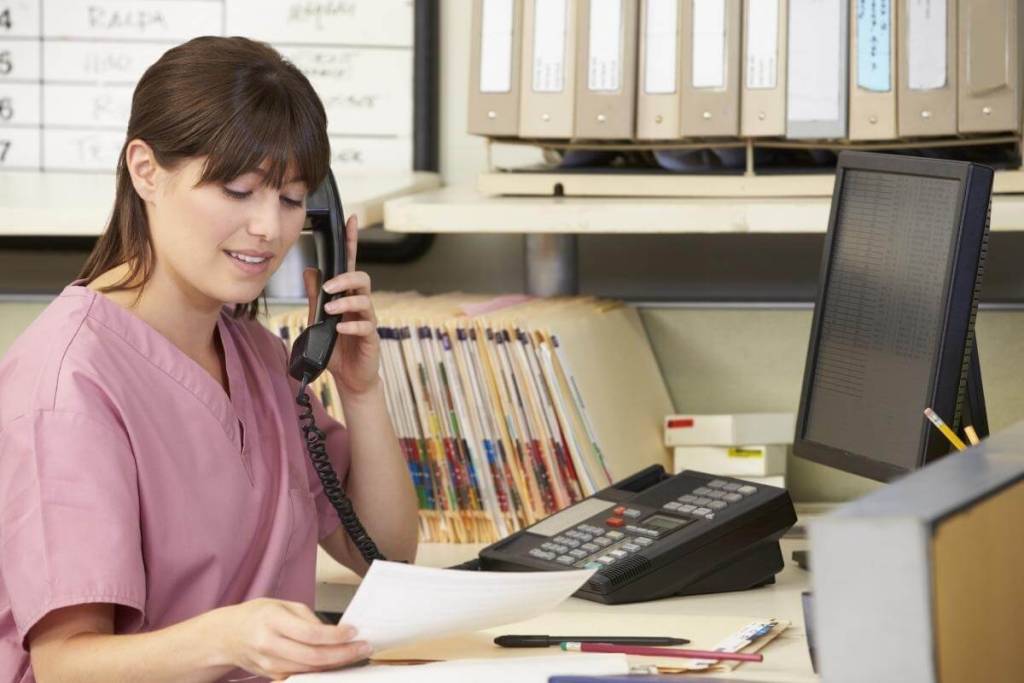 Nurse making phone calls at nurse station, following up claims and confirming patient records.