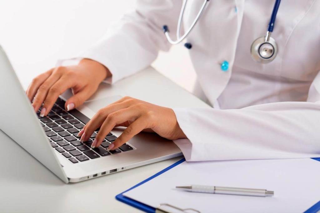 What Is Oncology Coding - Oncology doctor using laptop typing patient data. 