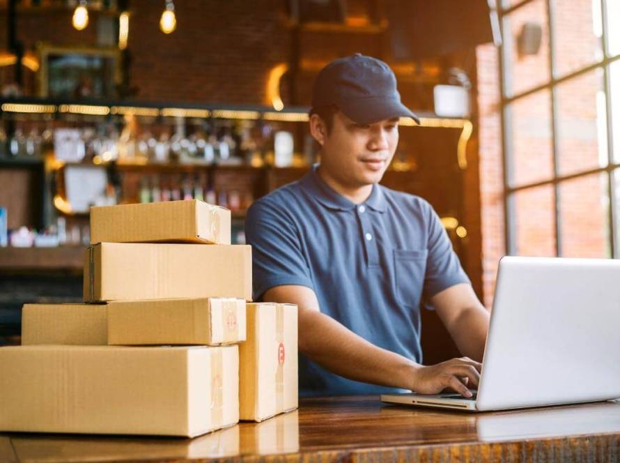 Advantages of outsourcing ecommerce - Young business owner preparing boxes of orders for customer delivery. Online shopping, ecommerce, online sales.