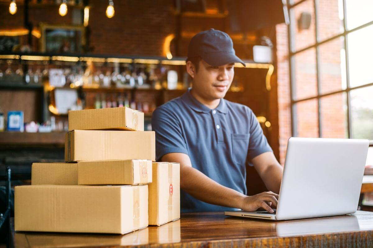 Advantages of outsourcing ecommerce - Young business owner preparing boxes of orders for customer delivery. Online shopping, ecommerce, online sales.