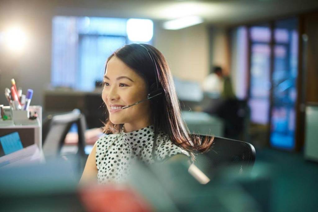 Call Centers and Customer Service - Female call center worker takes a call with a smile on her face.
