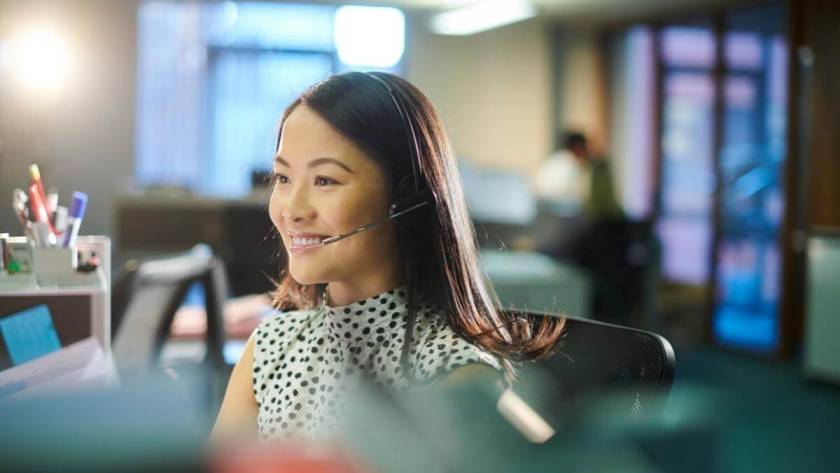 Call Centers and Customer Service - Female call center worker takes a call with a smile on her face.