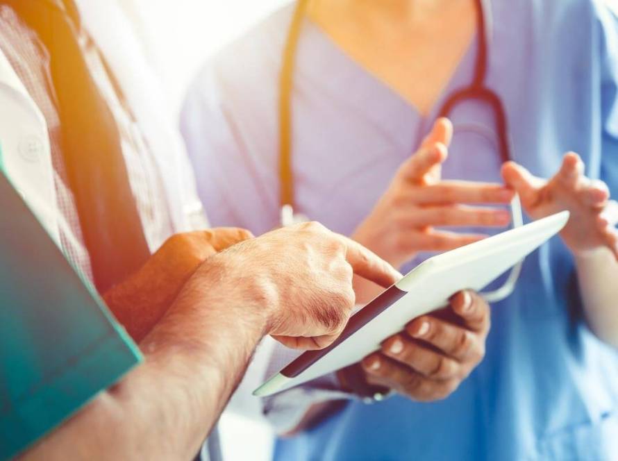 Medical Coding Company- Doctor medical team discusion about patient case using tablet or handheld computer monitor.