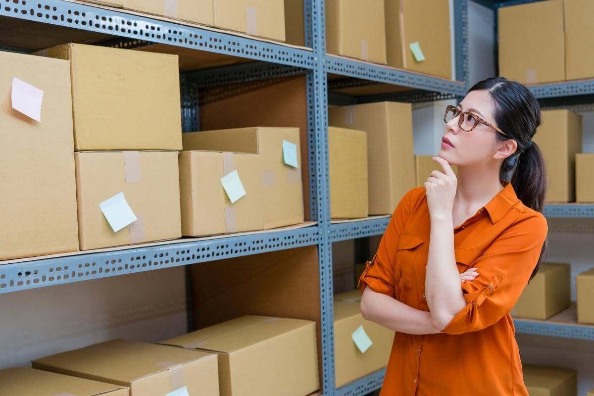 Young busineswoman looking at her producst in a storage room. 