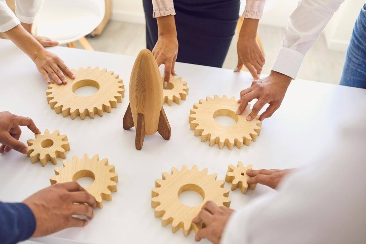 Business people around office table with rocket and cogwheels deciding on company strategy