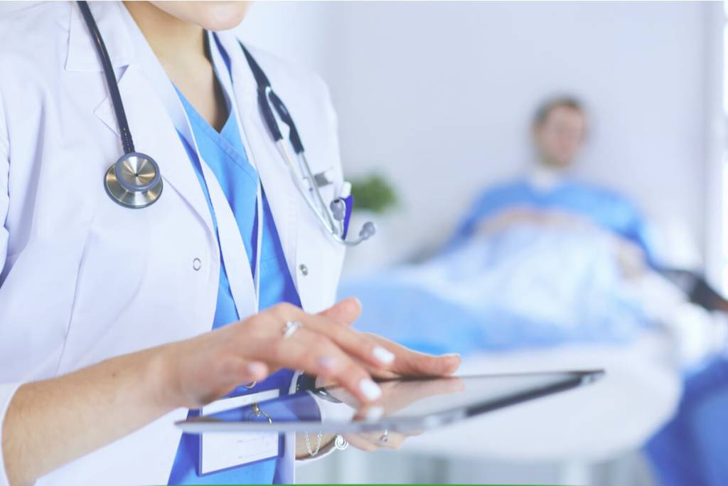 Outsourcing Oncology Medical Billing Services - Female doctor using tablet computer in hospital lobby