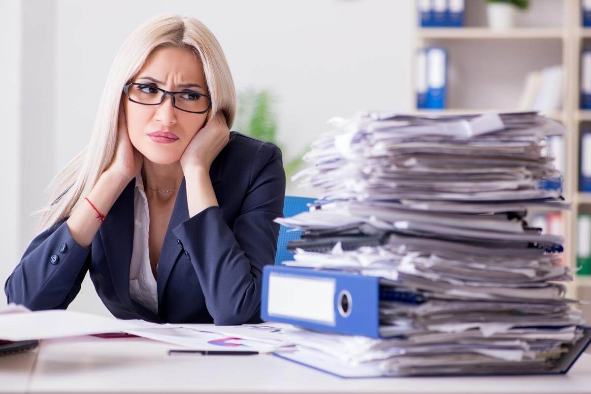 Busy businesswoman working in an office looking at piles of documents