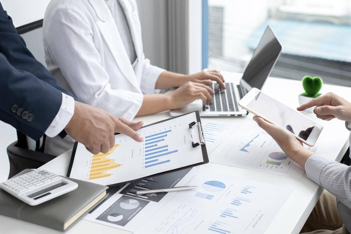 Business team meeting and data presentation, with office worker entering data on his laptop. 