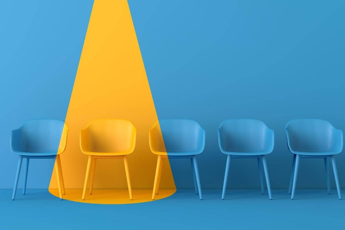 Yellow chair standing out from the crowd. Business hiring and training concept.