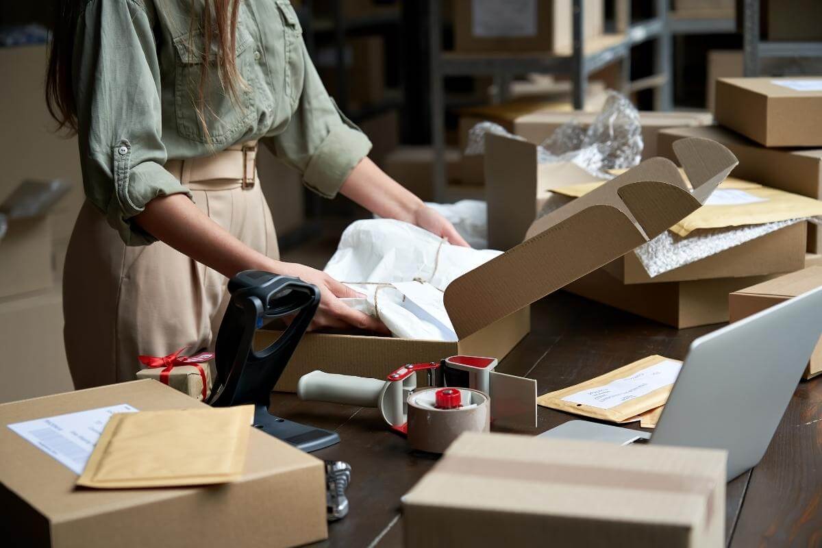 Closeup view of female online seller, small business owner manual packing products. 