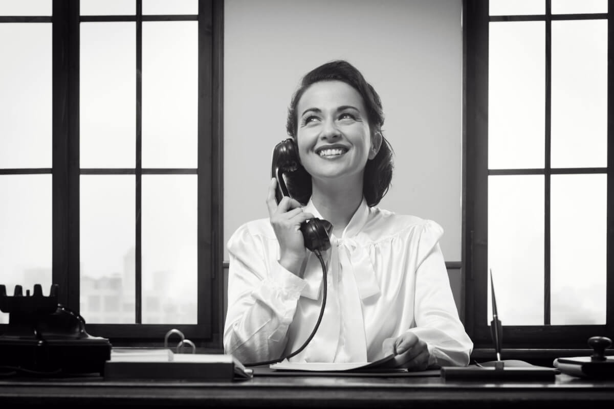 Smiling vintage receptionist working at office desk and smiling