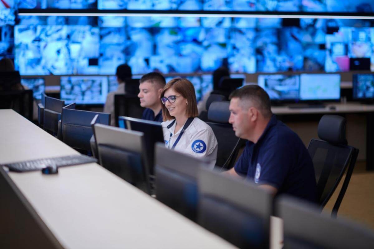Group of security data center operators working in a CCTV monitoring room. 