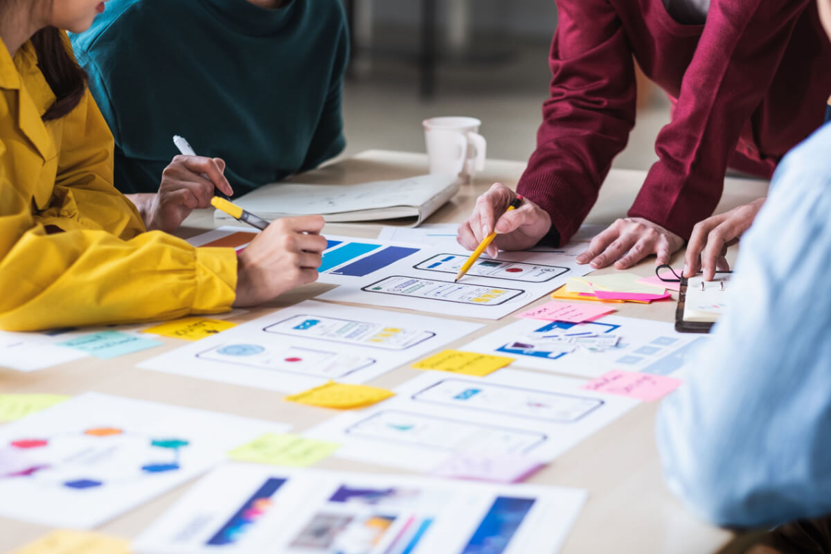 Close up ux developer and ui designer brainstorming about mobile app interface wireframe design on table with customer breif and color code at modern office.