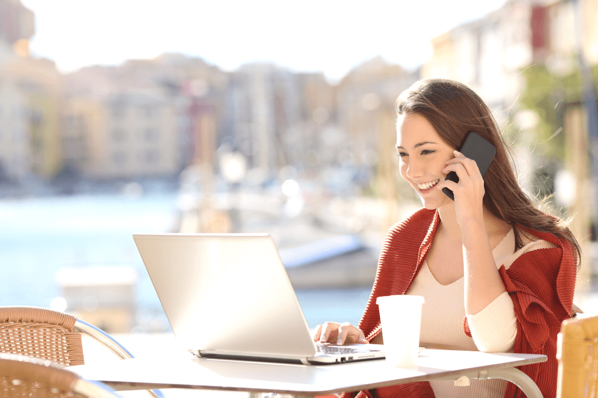 Girl calling customer service on mobile phone in a bar terrace. Happy Customer talking to contact center agents