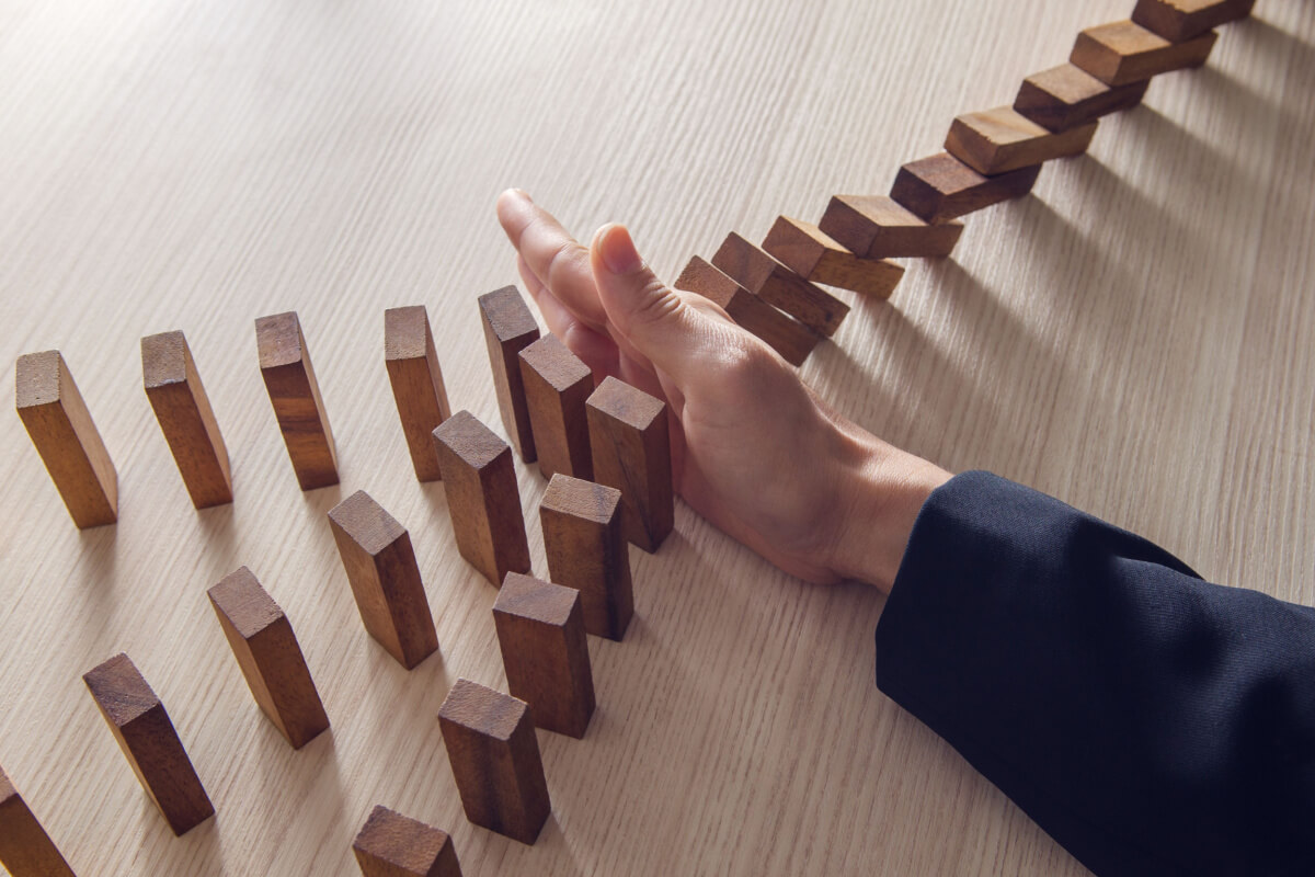 Risks of Business Process Outsourcing for Healthcare_Businesswoman hand stopping the domino wooden effect concept for business. 