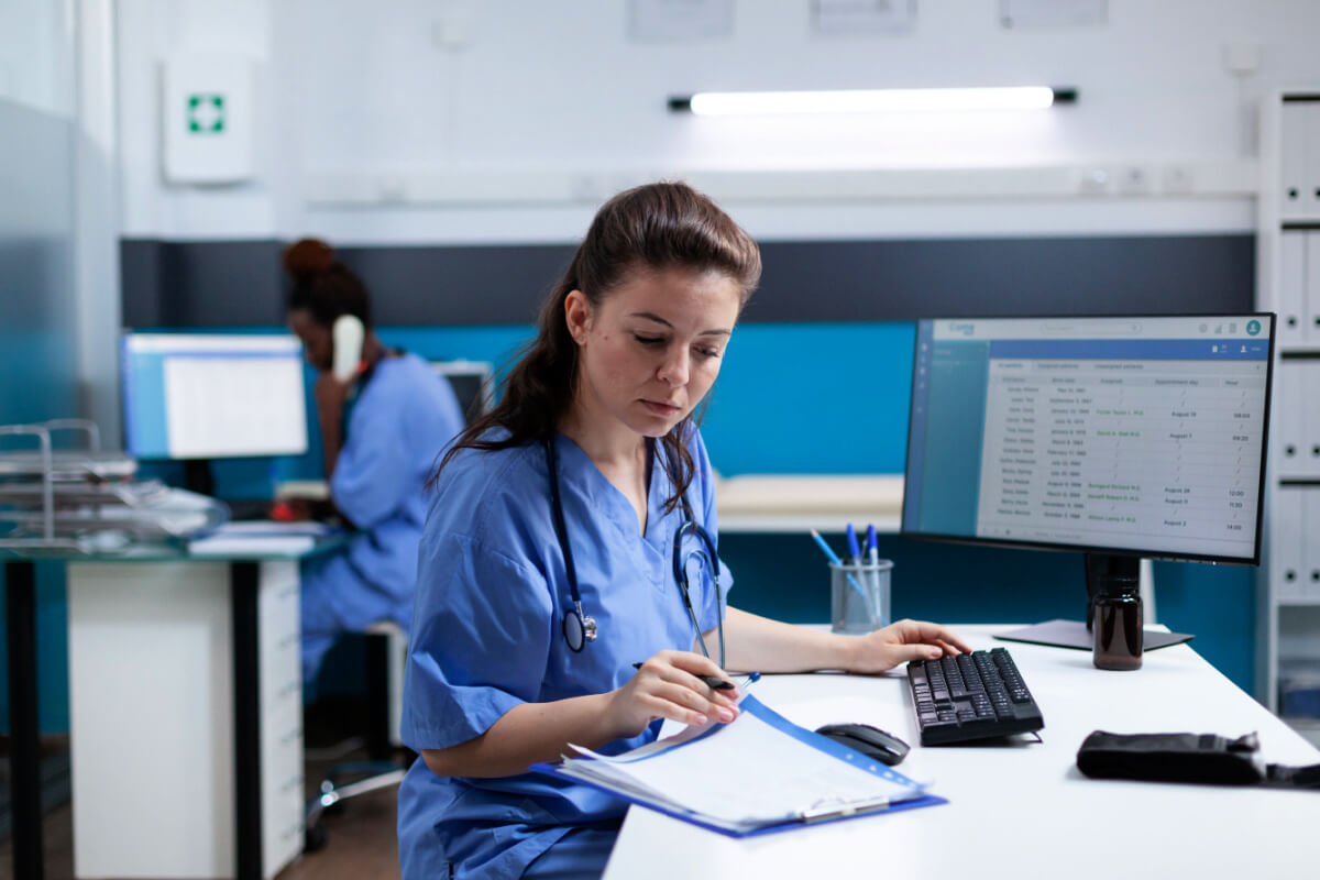 Pharmacist nurse with stethoscope analyzing healthcare treatment on medical documents typing sickness expertise working in hospital examination office. Woman asisstance checking disease results 